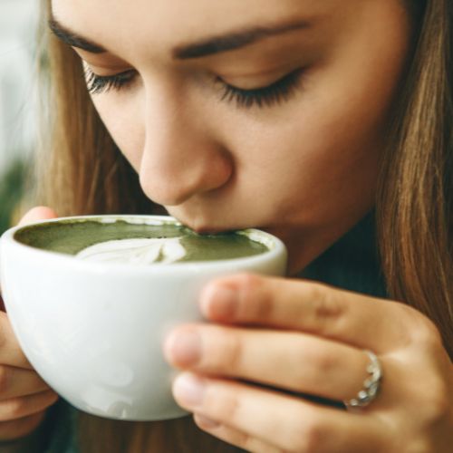 Vrouw nipt aan een heet kopje Matcha thee.