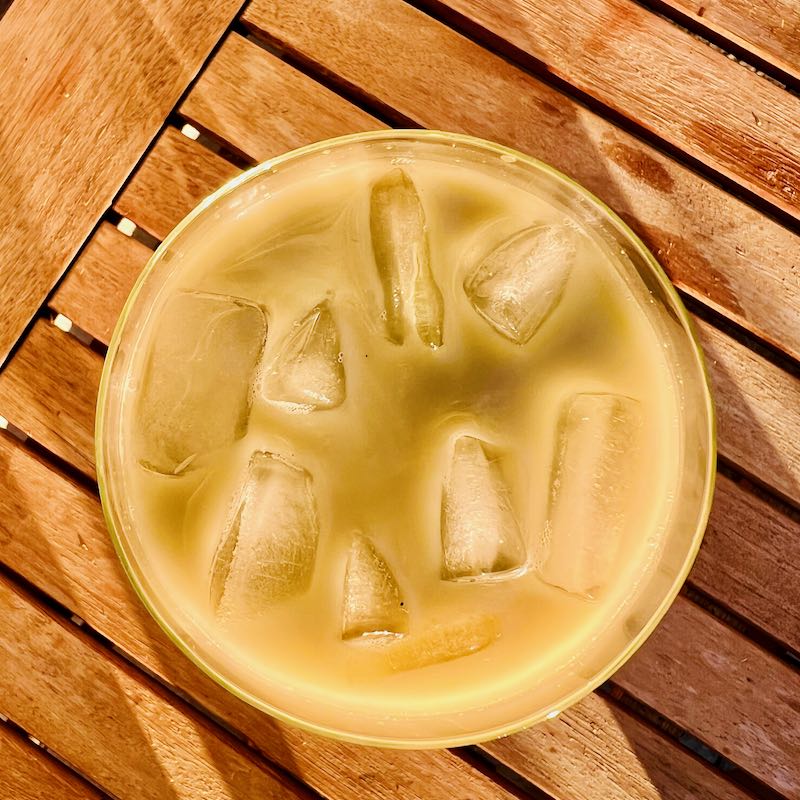 Top view of glass filled with Chilled Matcha Latte. Ice cubes float in the glass.